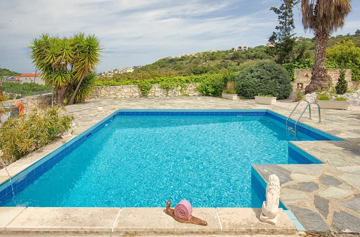 Cretan villa private pool surrounded by tropical garden and palm trees